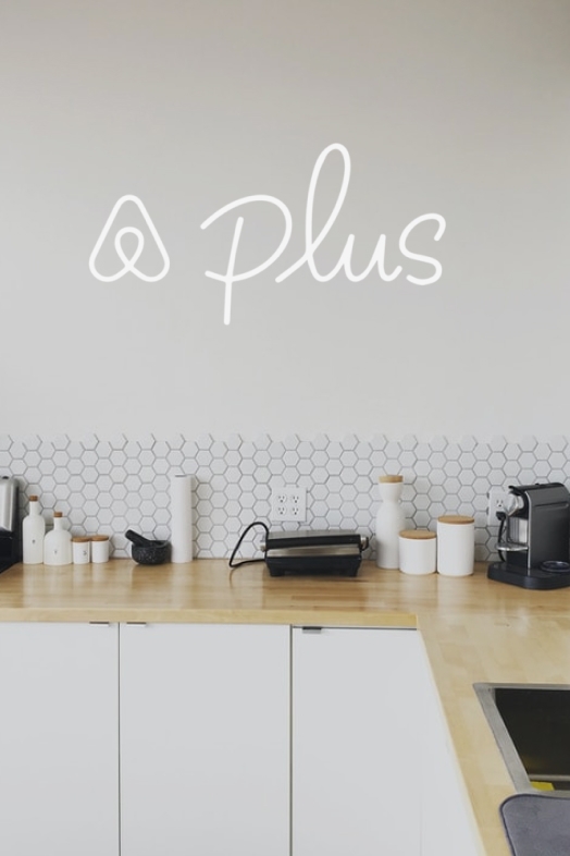 Airbnb Plus logo with the apartment's kitchen in the background.